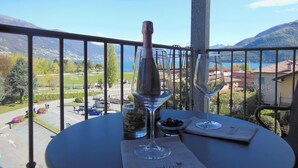 A balcony with a table set for two, overlooking a scenic view of a lake and mountains. - Hotel Giardino (Cannobio)