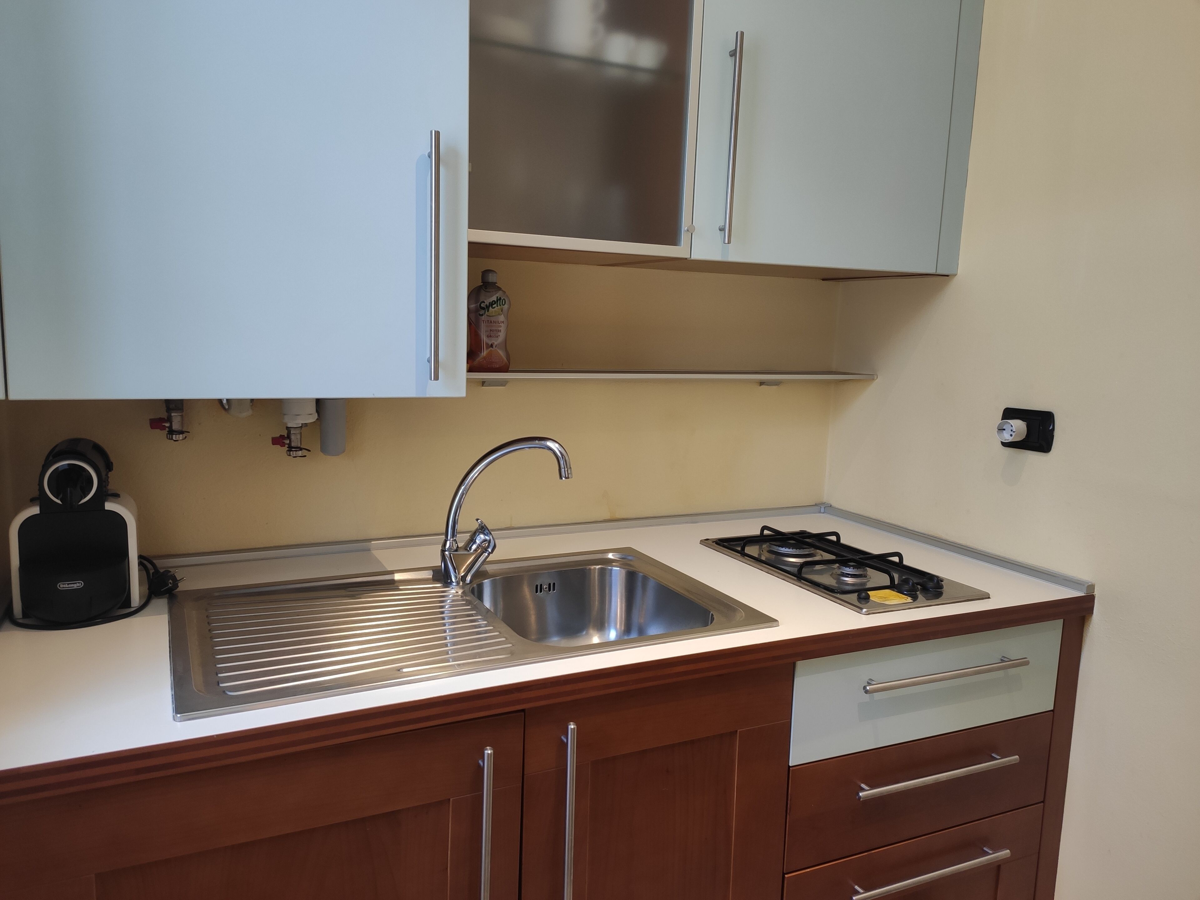 A compact kitchen with a stainless steel sink, a gas stove, and wooden cabinets.