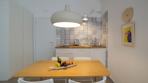 A modern kitchen with a wooden table set for dining, featuring a fruit bowl and white chairs. - Salsedine Sea View (Salerno)