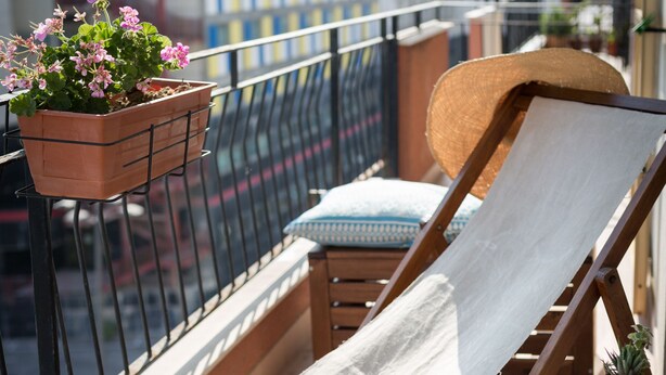 A balcony with a wooden chair, a small table with a tray, a potted plant, and a view of buildings. - Salsedine Sea View (Salerno)