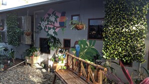 A courtyard with a wooden bench, potted plants, and a wall mural. - Summer House Backpackers Cairns (Cairns North)