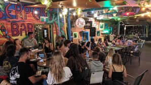 A crowded bar with tables and chairs, a mural on the wall, and a sign for 'Zac's'. - Summer House Backpackers Cairns (Cairns North)