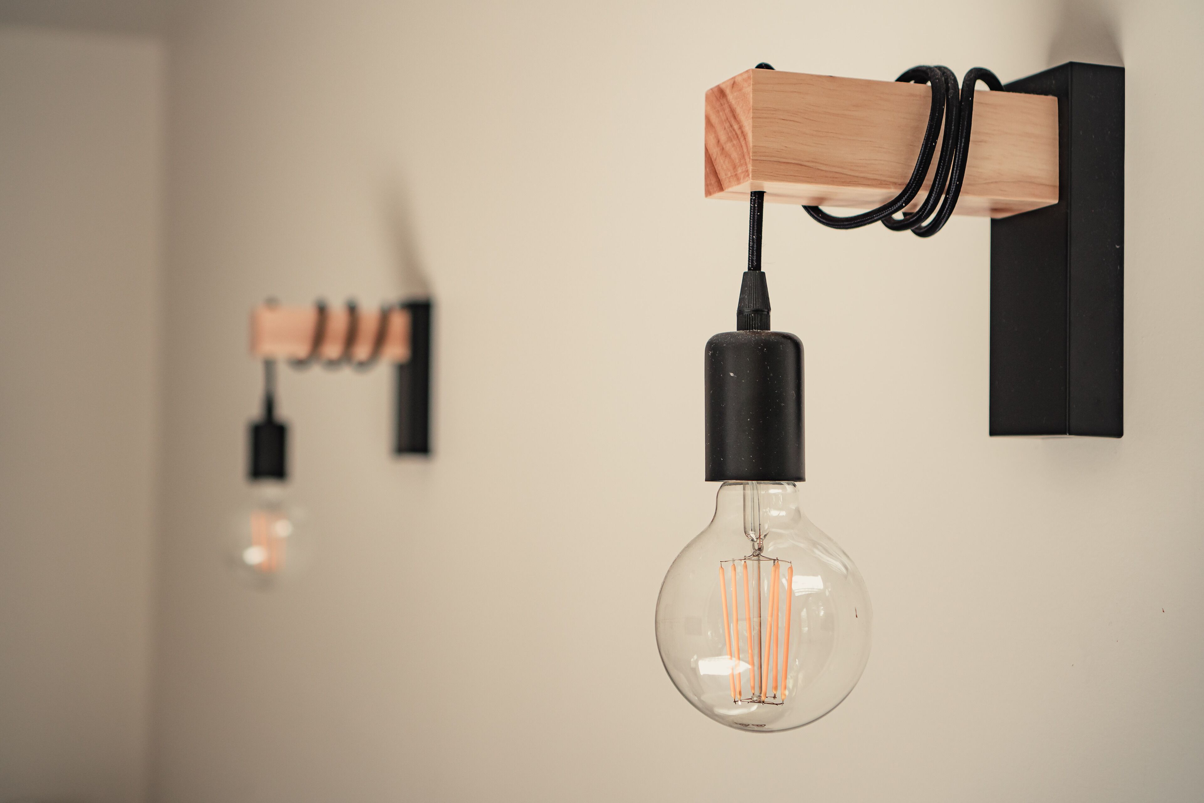 A modern light fixture with a clear glass bulb and a wooden base.