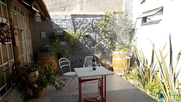 A small outdoor patio with a table and chairs, surrounded by potted plants and a rustic stone wall. - El Fresno (Mendoza)