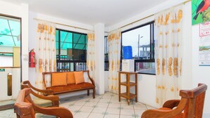 A room with a sofa, wooden chairs, a small table, and a window with curtains. - The Island Home (Puerto Ayora)
