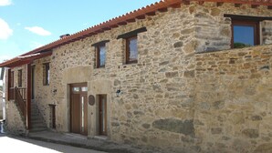 Un bâtiment en pierre avec un toit recouvert de tuiles, des portes en bois et de petites fenêtres.