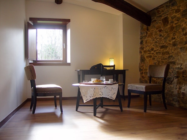 A cozy room with a stone wall, a wooden table with a lace tablecloth, and two chairs. - Candeias do Souto (Braganca)