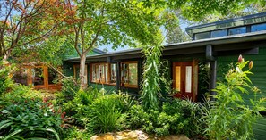 Una casa verde con jardín delantero, puertas de madera y una ventana con vista al cielo.