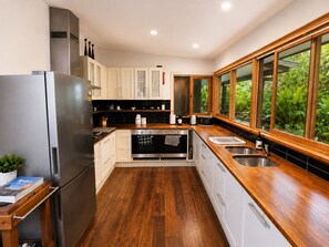 Una cocina moderna con refrigerador de acero inoxidable, encimeras de madera y un ventanal con vistas al verdor.