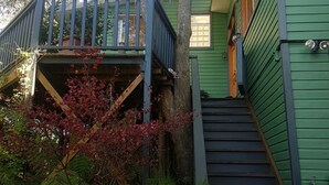 A green house with a wooden staircase leading to a porch. - Black Cockatoo - Secret Garden Mountains Home (Katoomba)