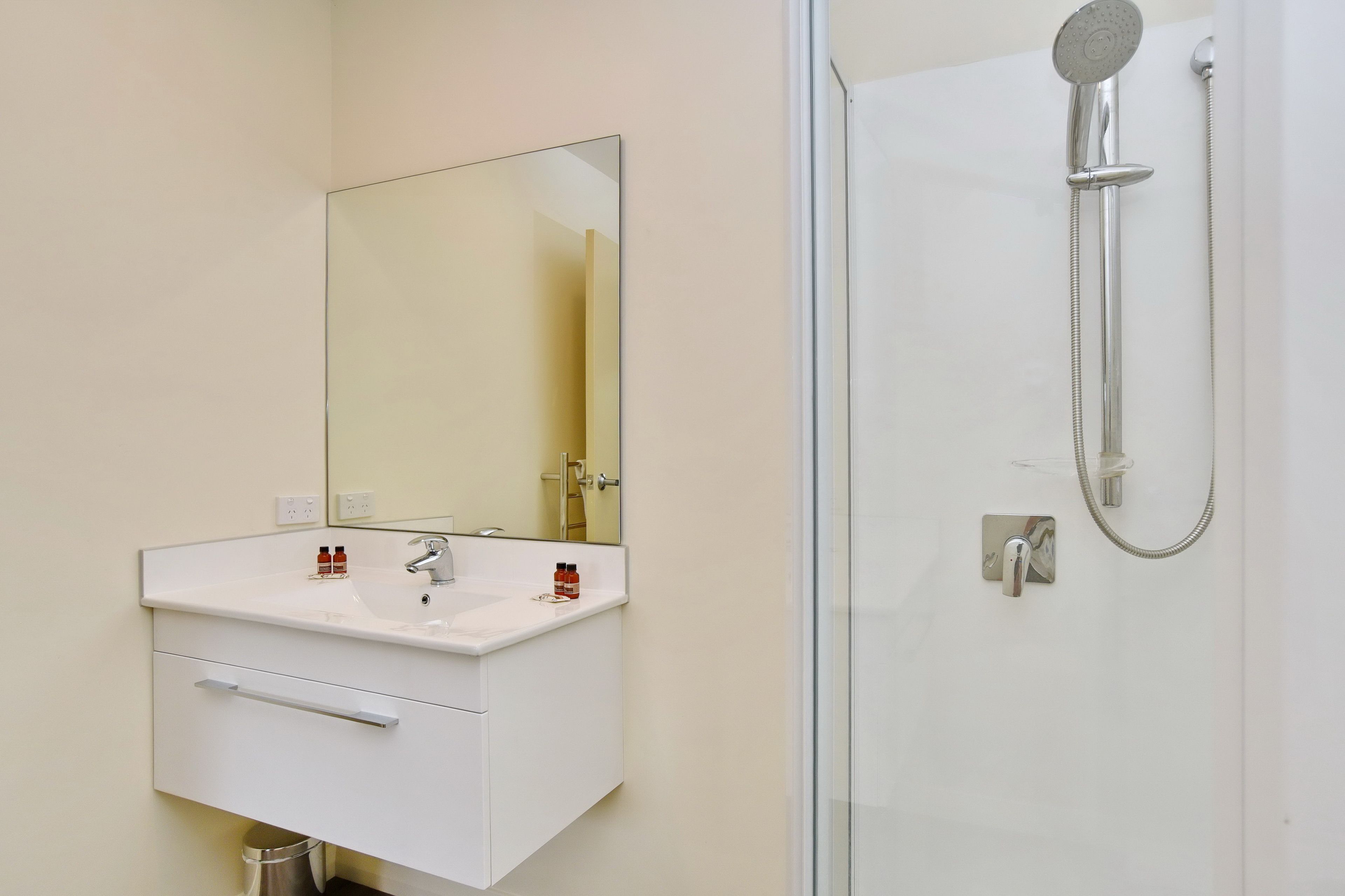 A bathroom with a white sink, mirror, and shower.
