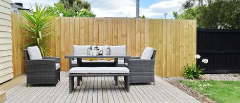 A deck with a table and two chairs, surrounded by a wooden fence.