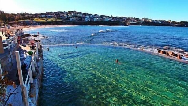 Un pueblo costero con aguas azules cristalinas, un litoral rocoso y edificios a lo largo de la costa.