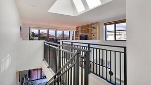 Un interior moderno con una escalera, tragaluces y ventanas amplias que ofrecen vistas al exterior.