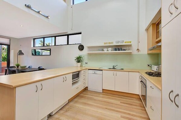 Una cocina moderna con armarios blancos, encimera de madera y horno empotrado.