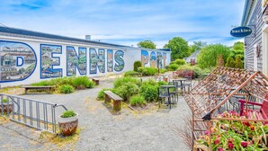 A courtyard with a mural of a town, outdoor seating, and a sign for 'Buckies Biscuits'.