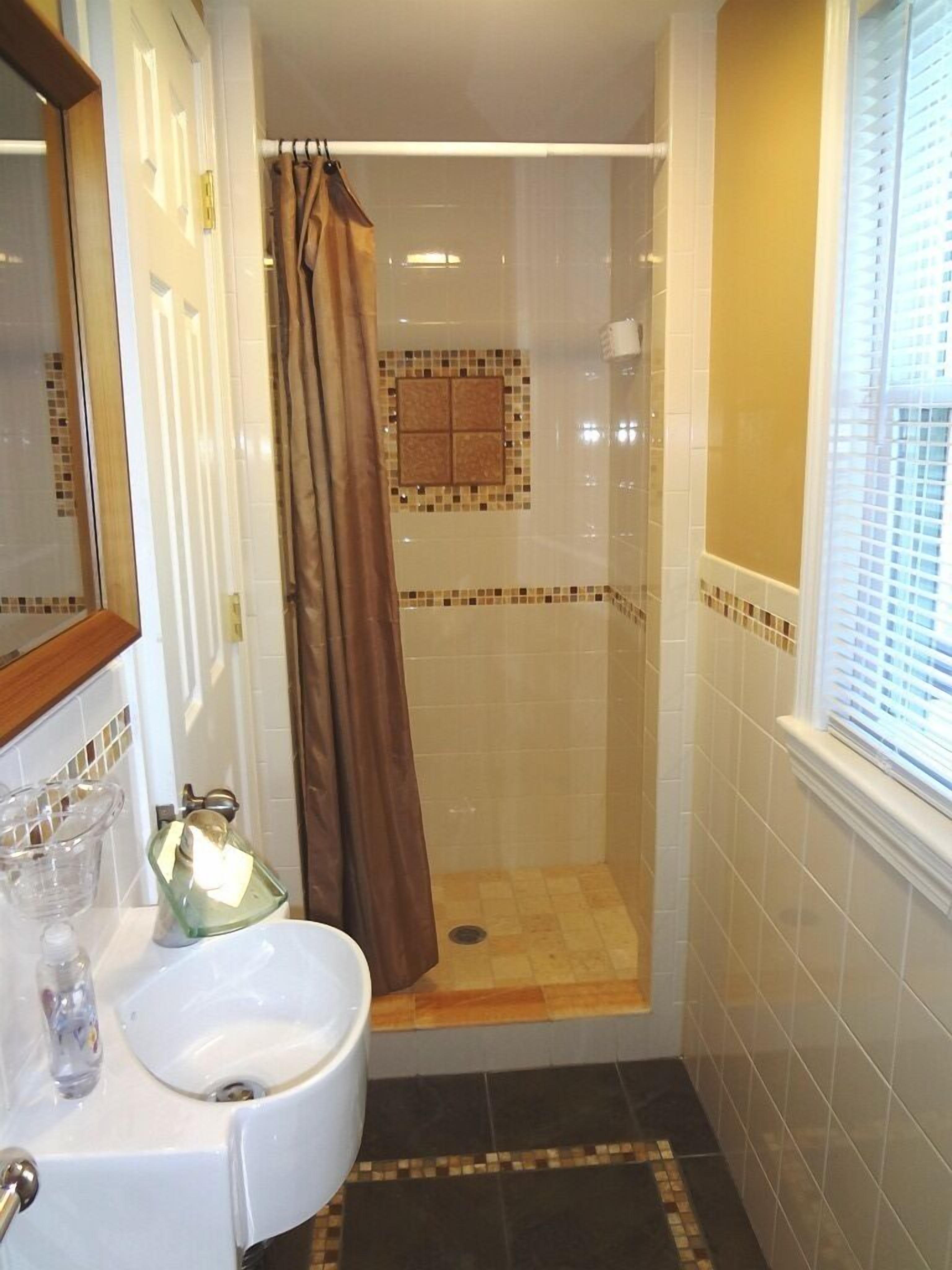 Une salle de bain avec une douche, un lavabo et une fenêtre.