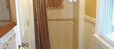Une salle de bain avec une douche, un lavabo et une fenêtre.