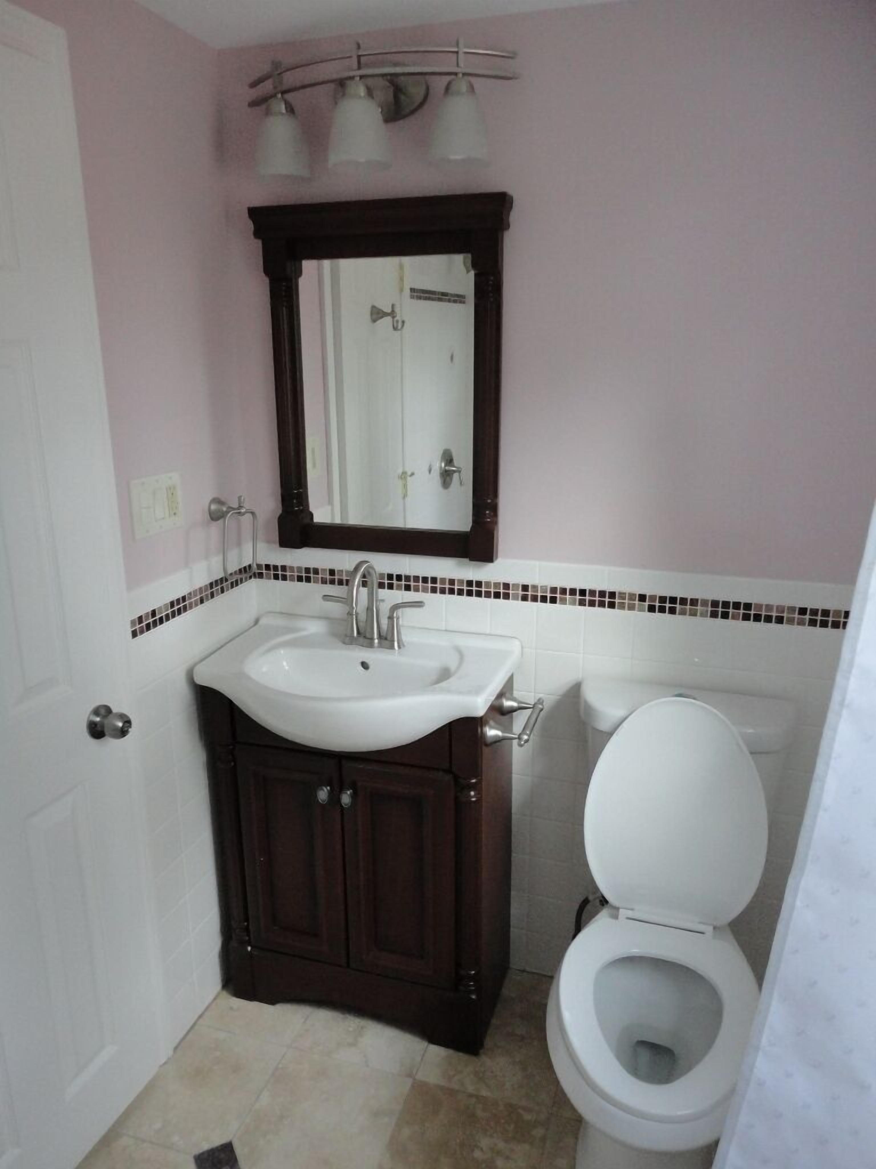 Un baño con un lavabo blanco, un mueble de madera oscura y un inodoro.