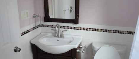 Un baño con un lavabo blanco, un mueble de madera oscura y un inodoro.