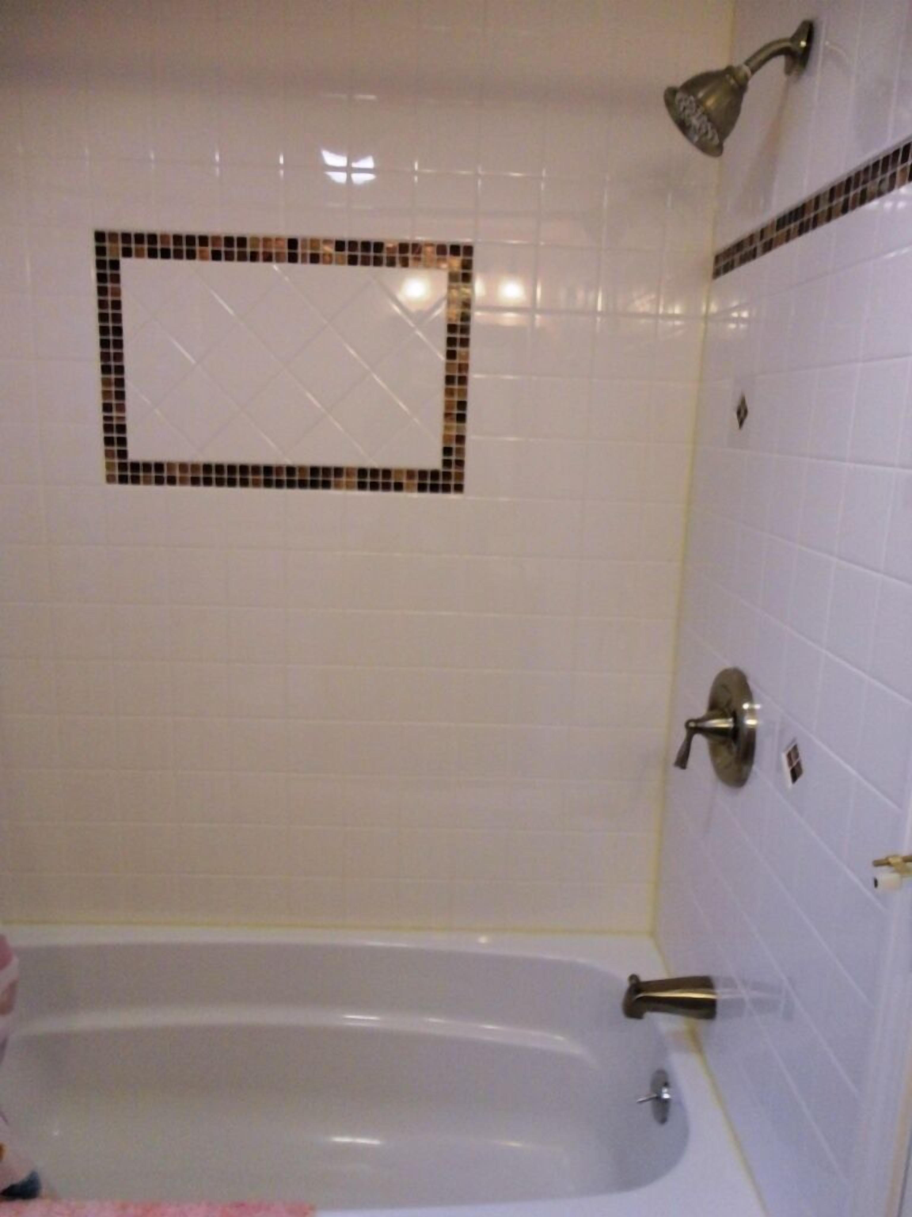 A bathroom with a bathtub, a shower, and a wall-mounted mirror.