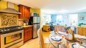A kitchen with a stove, microwave, and refrigerator. There is a dining area with a table set for two.