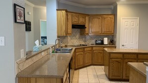 Una cocina con armarios de madera, un lavamanos de acero inoxidable, un horno empotrado y un salpicadero de azulejos.