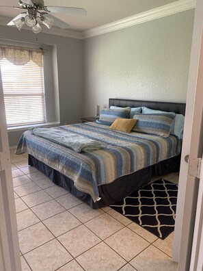 Cozy retreat with a large bed, ceiling fan, and window with blinds.