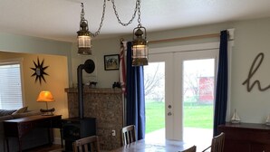 A dining room with a wooden table and chairs, a fireplace, and a view of the outdoors. - The Dayton Lake Place (Dayton)