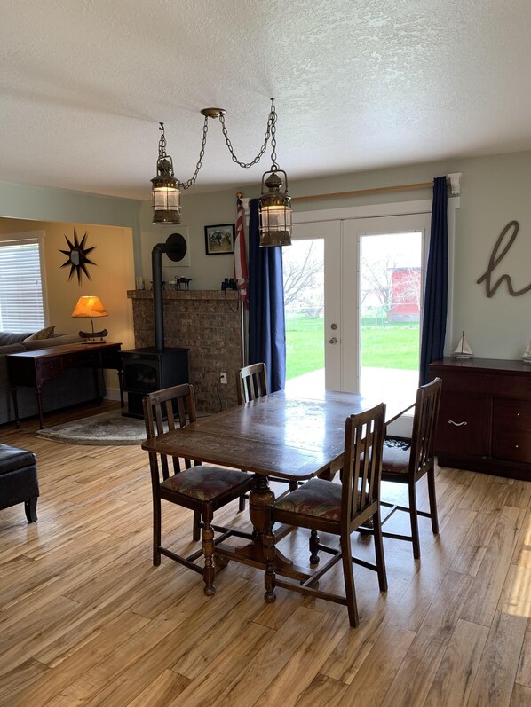 A dining room with a wooden table and chairs, a fireplace, and a view of the outdoors.