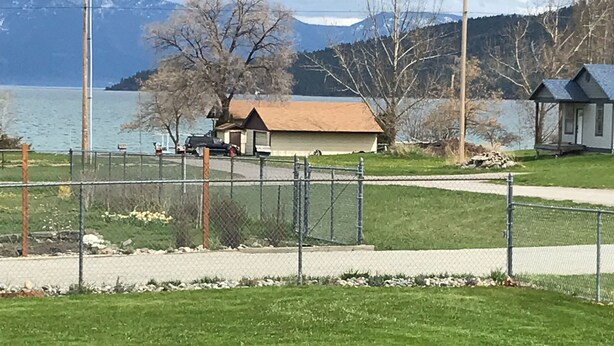A fenced grassy area with a small building and a dock by a lake, surrounded by mountains. - The Dayton Lake Place (Dayton)