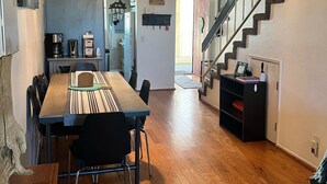 A spacious dining area with a wooden table and chairs, a hanging light fixture, and a staircase leading to another level. - Quiet Beautiful Beach Condo steps to beach, We are the best deal! (Port Hueneme)
