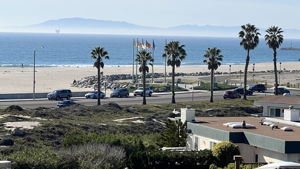 A coastal road with palm trees, a beach, and a view of the ocean. - Quiet Beautiful Beach Condo steps to beach, We are the best deal! (Port Hueneme)