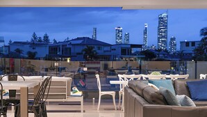 A modern living room with a city skyline view, white furniture, and a glass partition. - Relaxed waterfront living (Gold Coast)