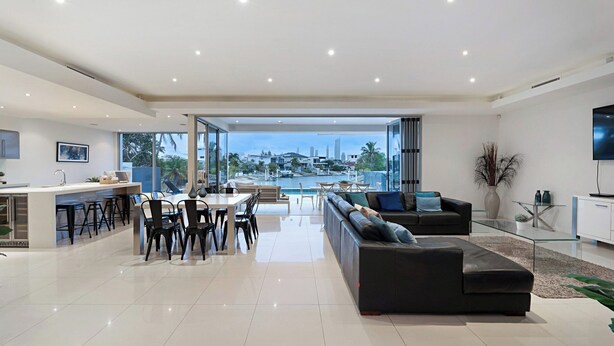 A modern living room with a large sofa, dining area, and kitchen. - Relaxed waterfront living (Gold Coast)