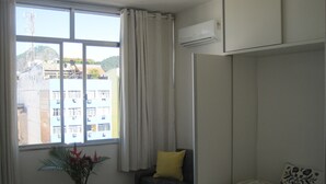 A bedroom with a bed, a chair, a table, and a window.