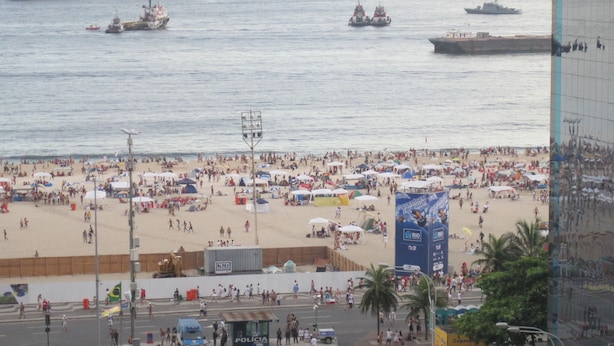 A beach with people, tents, and boats in the water.