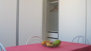 A room with a pink table, a chair, and a fruit bowl with bananas and apples.