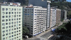 A multi-story hotel with a prominent sign, a street in front, and a mountain in the background.