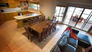 A spacious kitchen with wooden cabinets, a central island, and a dining area with a black leather sofa. - Limestone Ridge River Getaway (Tailem Bend)