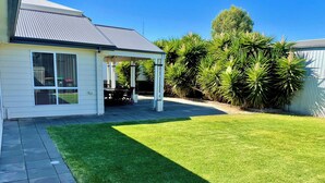 A residential backyard with a patio, a covered outdoor seating area, and a well-maintained lawn. - Moontana @ Moonta Bay (Moonta Bay)