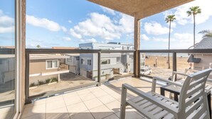 Un balcón con vista a una zona residencial, que incluye casas y palmeras.