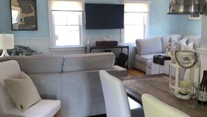 A living room with a sofa, chairs, a table, and a TV. - Charming 2br/2ba - steps 2 beach and all Ptown has to offer!  (Provincetown)