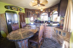 A kitchen with a stone island, wooden cabinets, and a large refrigerator.