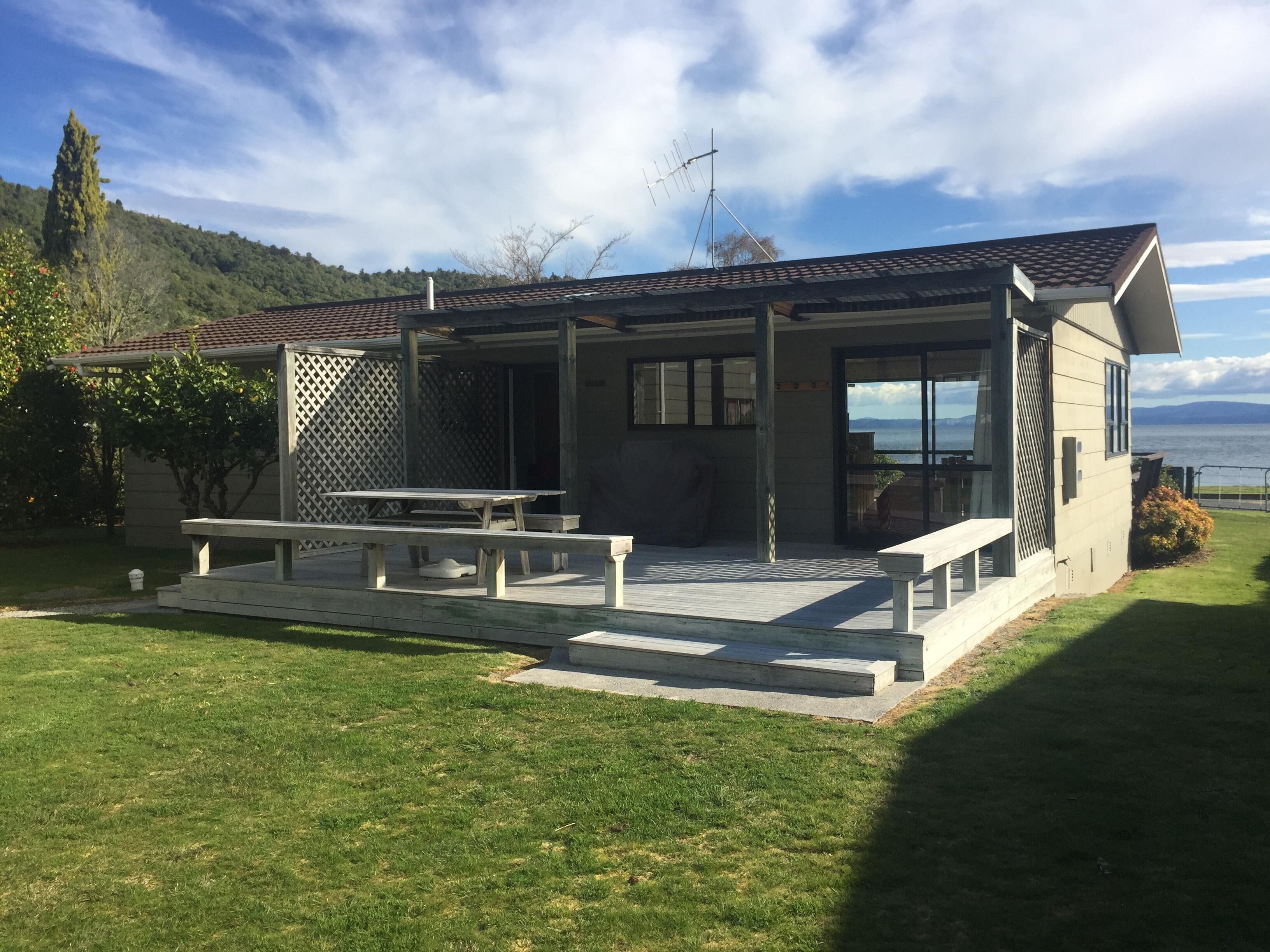 A modern house with a patio, a table, and a bench.