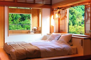 Een slaapkamer met een groot raam, houten wanden en een bed met wit beddengoed.