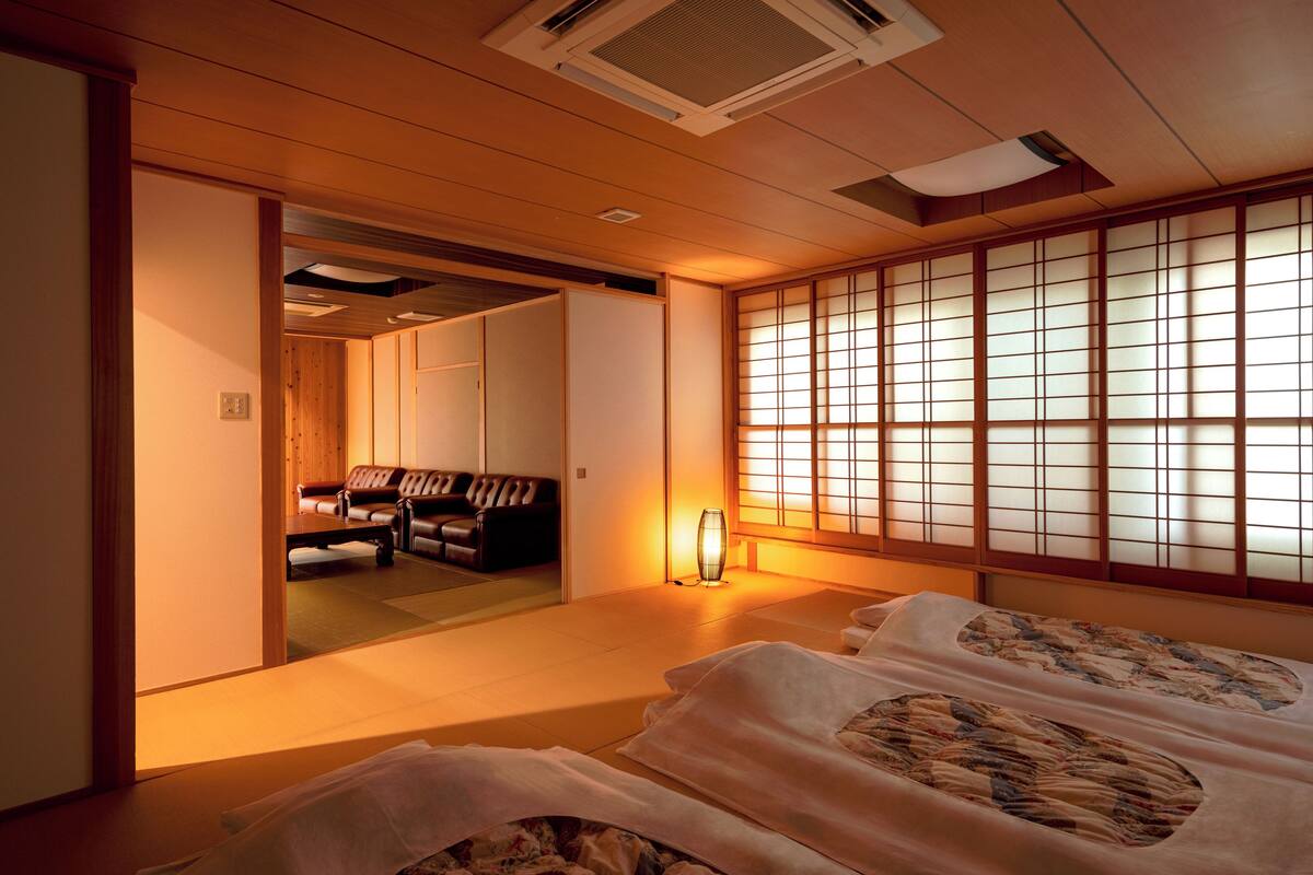 Een traditionele Japanse kamer met tatami vloeren, een lage tafel en een bank.