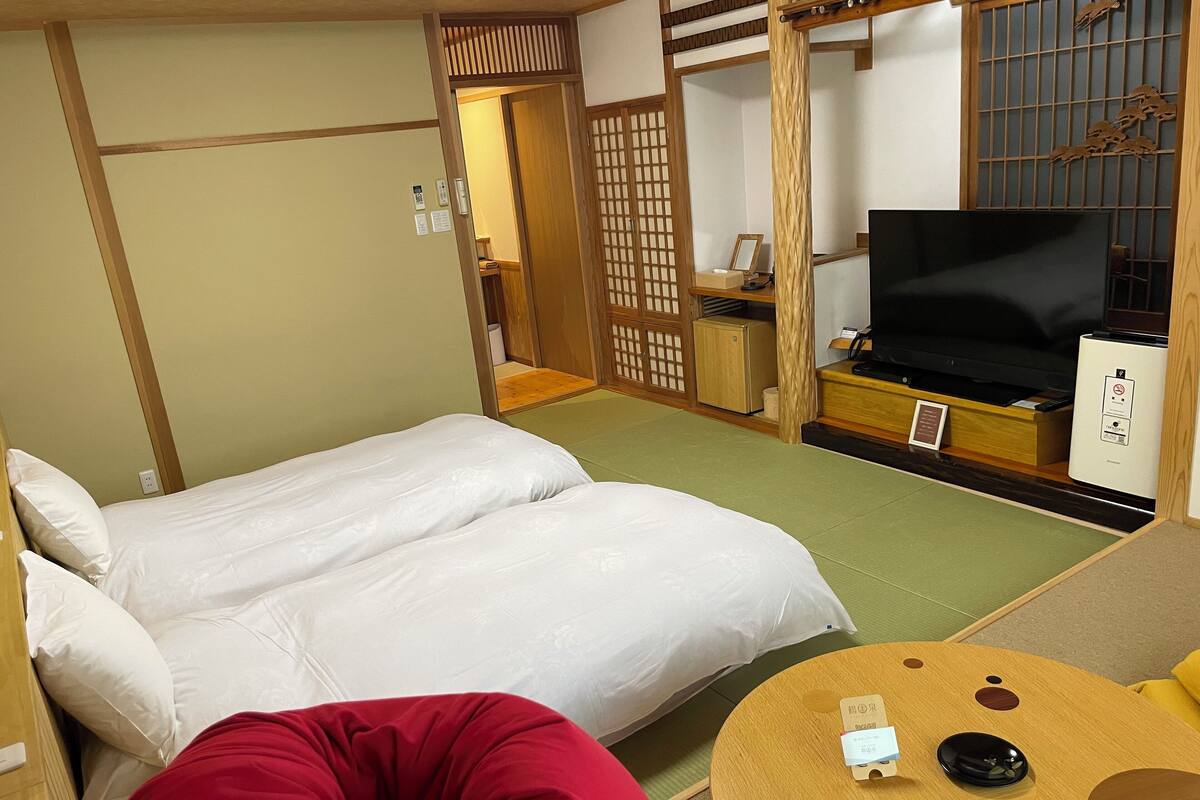 Een hotelkamer met een bed, een televisie, een kleine koelkast en een slaapbank.