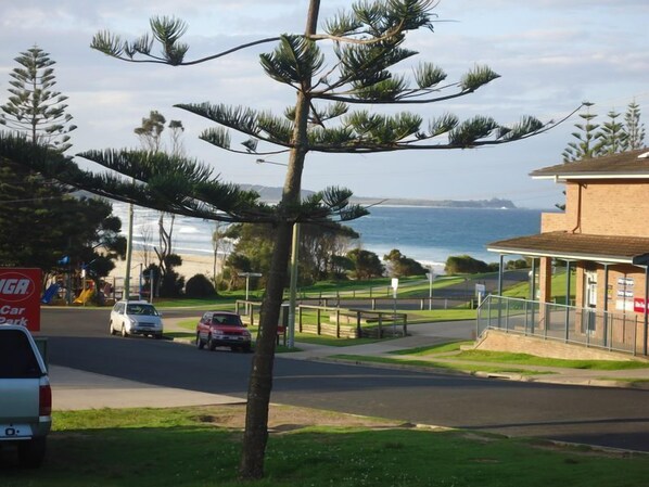 A coastal road with a car park sign, a building with a covered area, and a view of the sea.