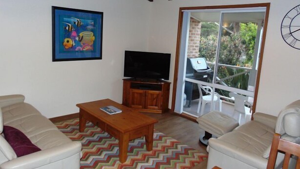 A living room with a television, a sofa, a coffee table, and a colorful rug.